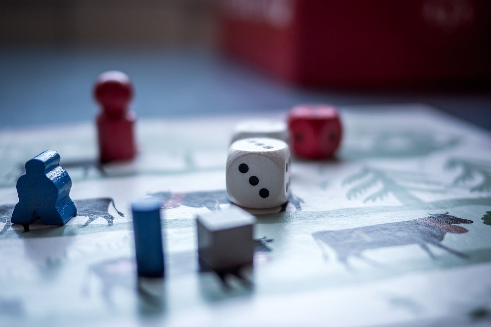 Close-up of dice and wooden game pieces on a board game, softly out of focus